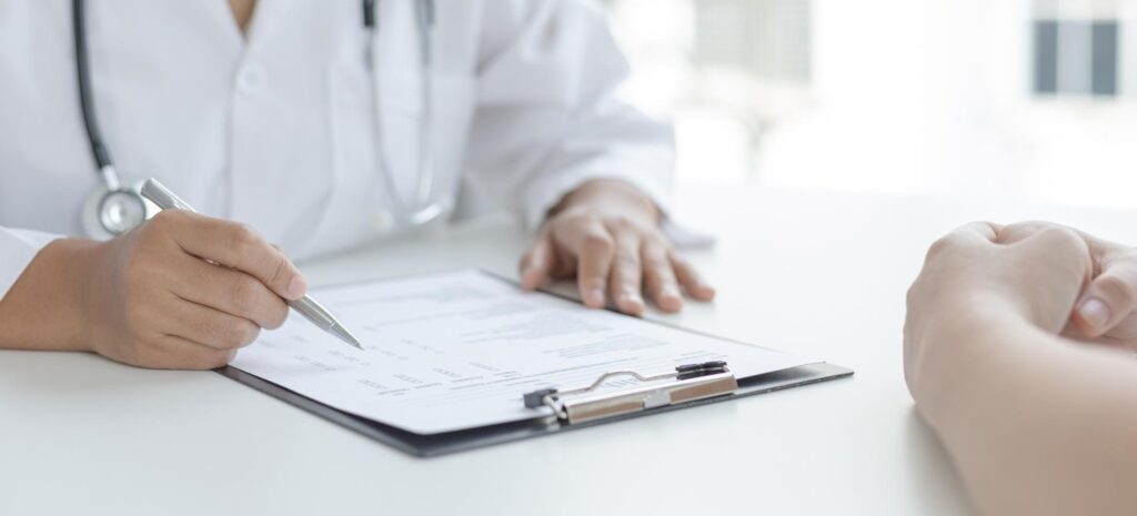 Doctor filling out a patient form on a clipboard